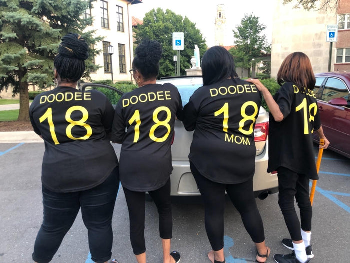 Four supporters wearing matching black softball jerseys back view