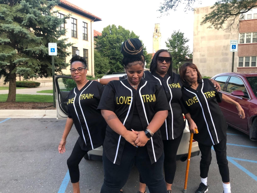 Four supporters wearing matching black softball jerseys front view