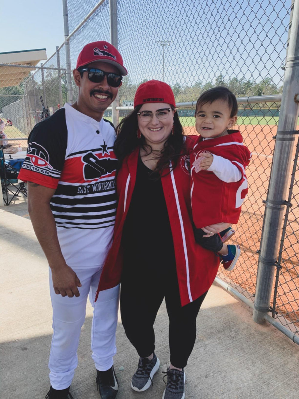 Family in baseball jerseys together at a ballfield